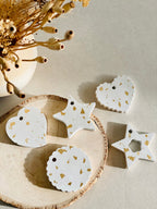 Décorations de sapin en béton et feuilles d’or présentées sur un rondin de bois sur une table