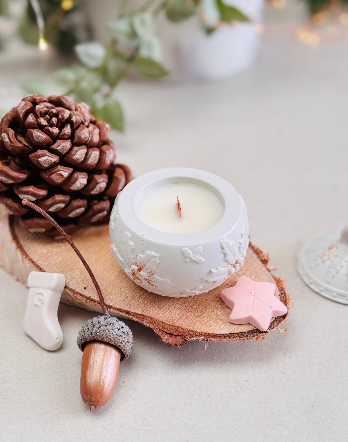 Bougie festive blanche au cœur d’une composition de Noël