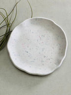 Coupelle ronde decorative en Jesmonite terrazzo gris et rose posé sur une table