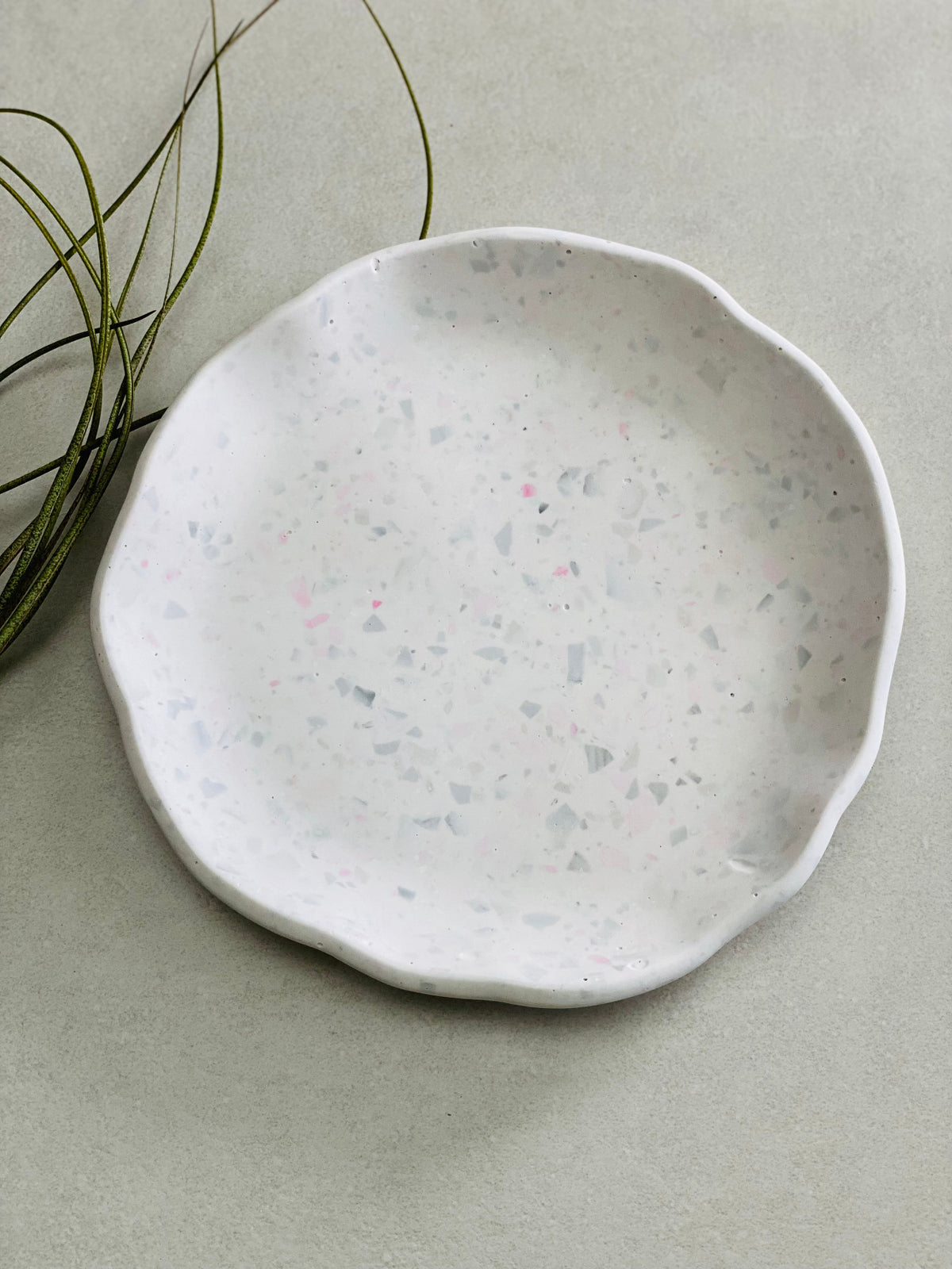 Coupelle ronde decorative en Jesmonite terrazzo gris et rose posé sur une table