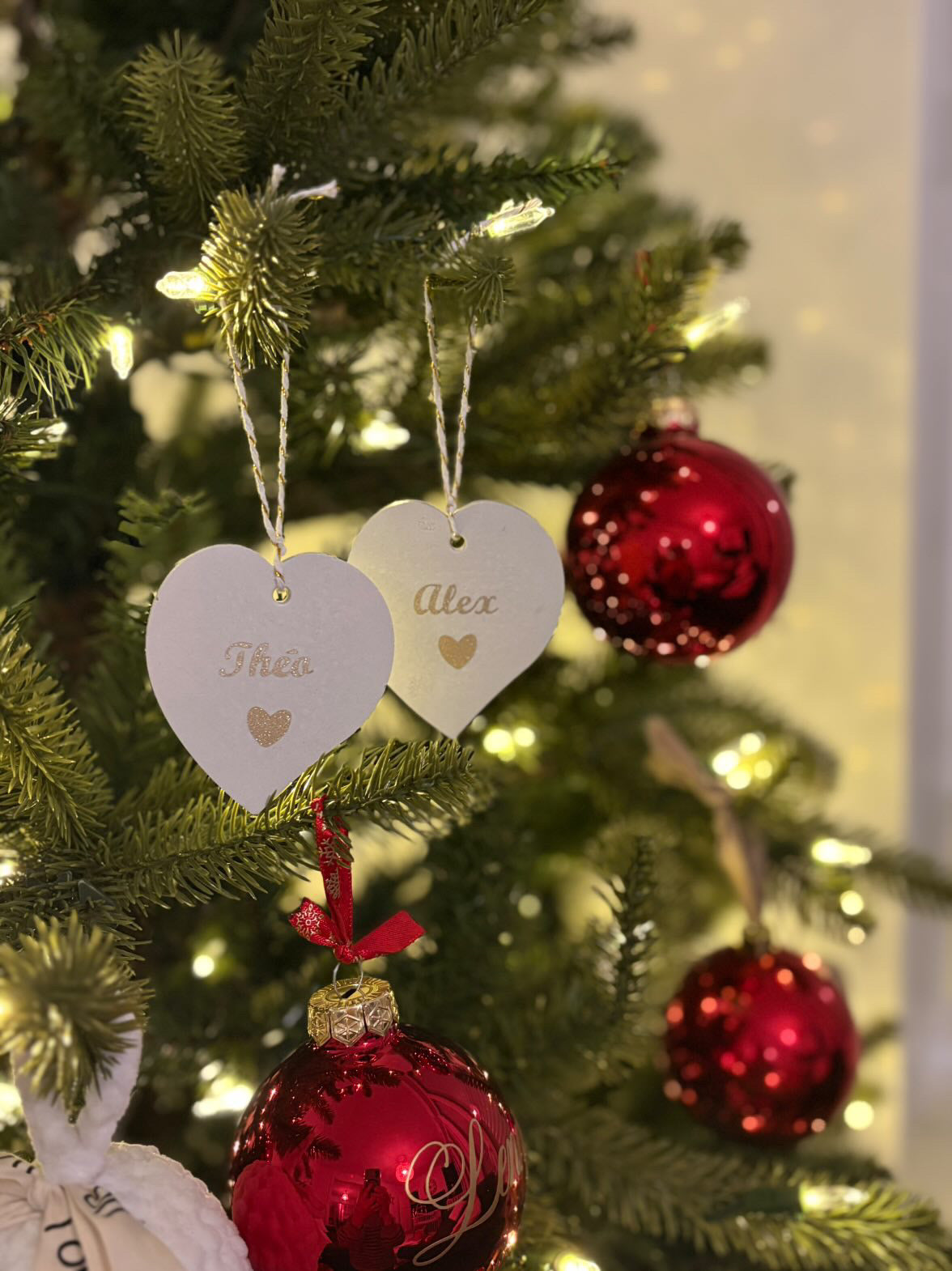 Les suspensions sur un sapin en forme de cœur avec les prénoms inscrits avec vinyle doré 