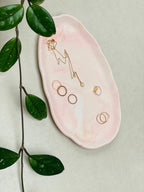 Plateau présentoir ovale en Jesmonite marbrée rose pêche avec des bijoux