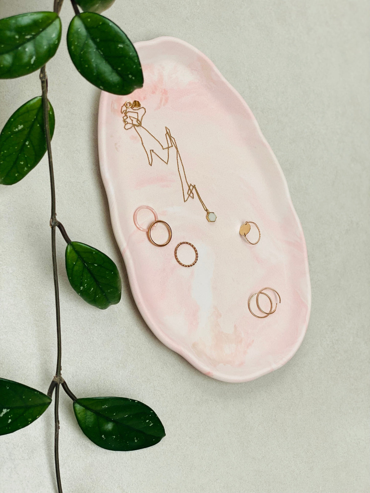 Plateau présentoir ovale en Jesmonite marbrée rose pêche avec des bijoux