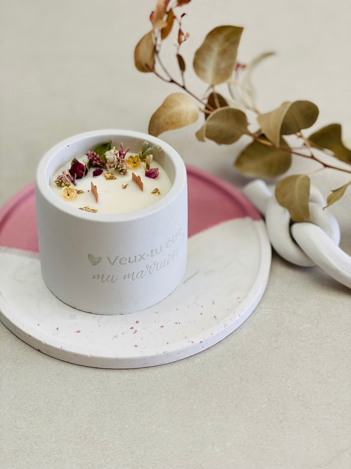 Bougie avec fleurs séchées posée sur un plateau rond 