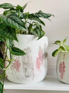 Grand cache-pot en béton motif craquelé rose et gris sur blanc avec une plante intérieur 
