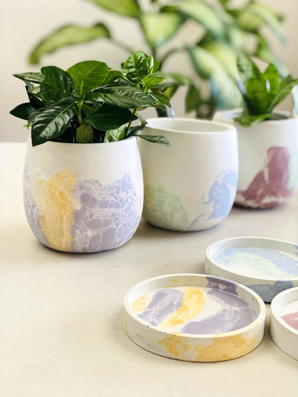 Vue d’ensemble des trois cache-pots moyens en béton craquelé dans les coloris Bleu Vert, Vert Magenta et Jaune Lilas
