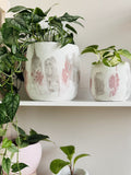 Deux cache-pots en béton grand et petit style craquelé rose et gris sur blanc avec des plantes intérieur 