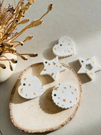Décorations de sapin en béton et feuilles d’or présentées sur un rondin de bois sur une table